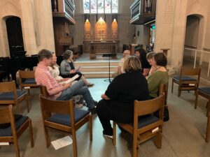 Several Forward Movement staff members sitting in a circle of chairs in a small chapel.